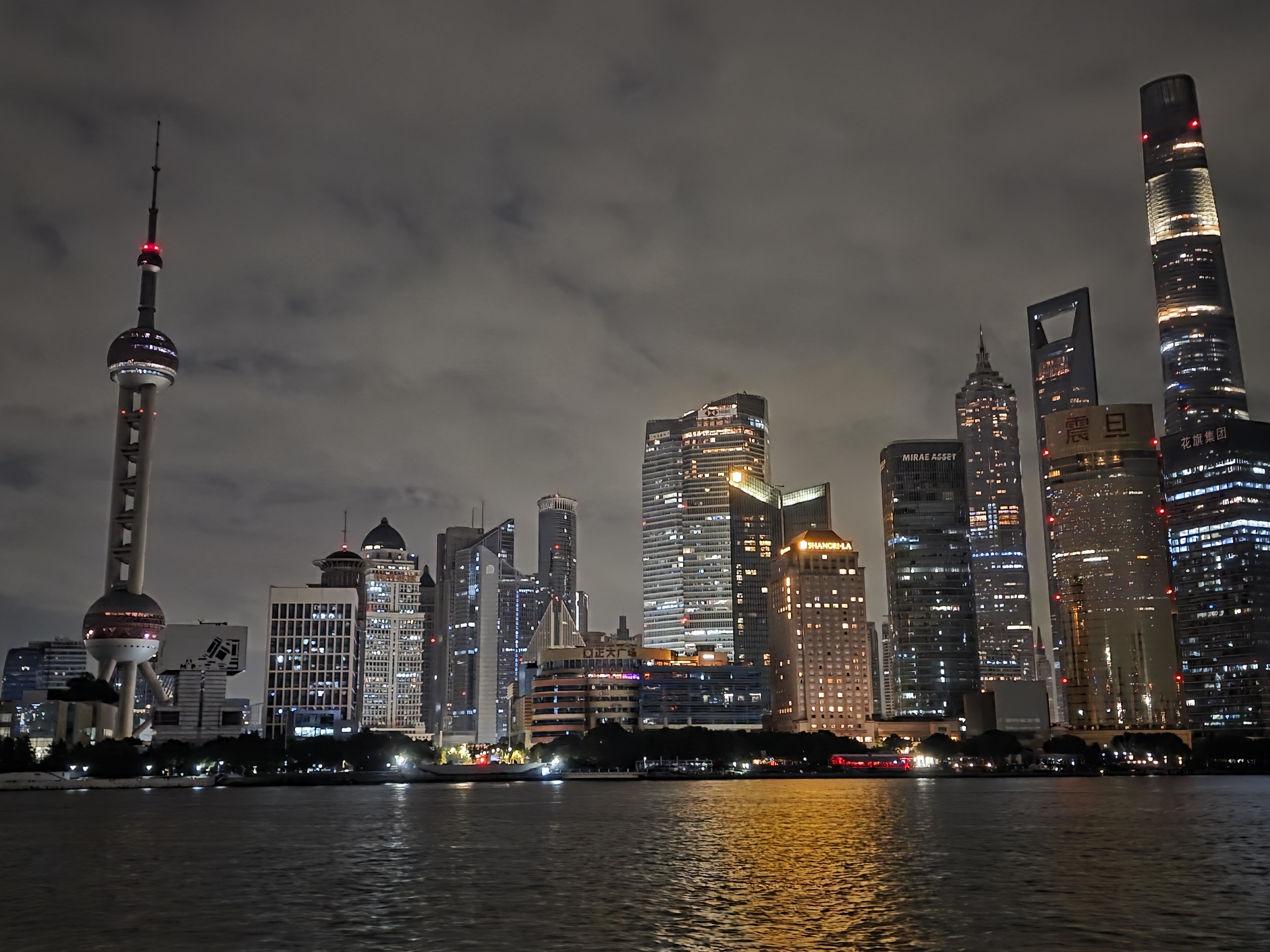 Shanghai's Pudong skyline, including the Oriental Pearl Tower, across the Huangpu River at night