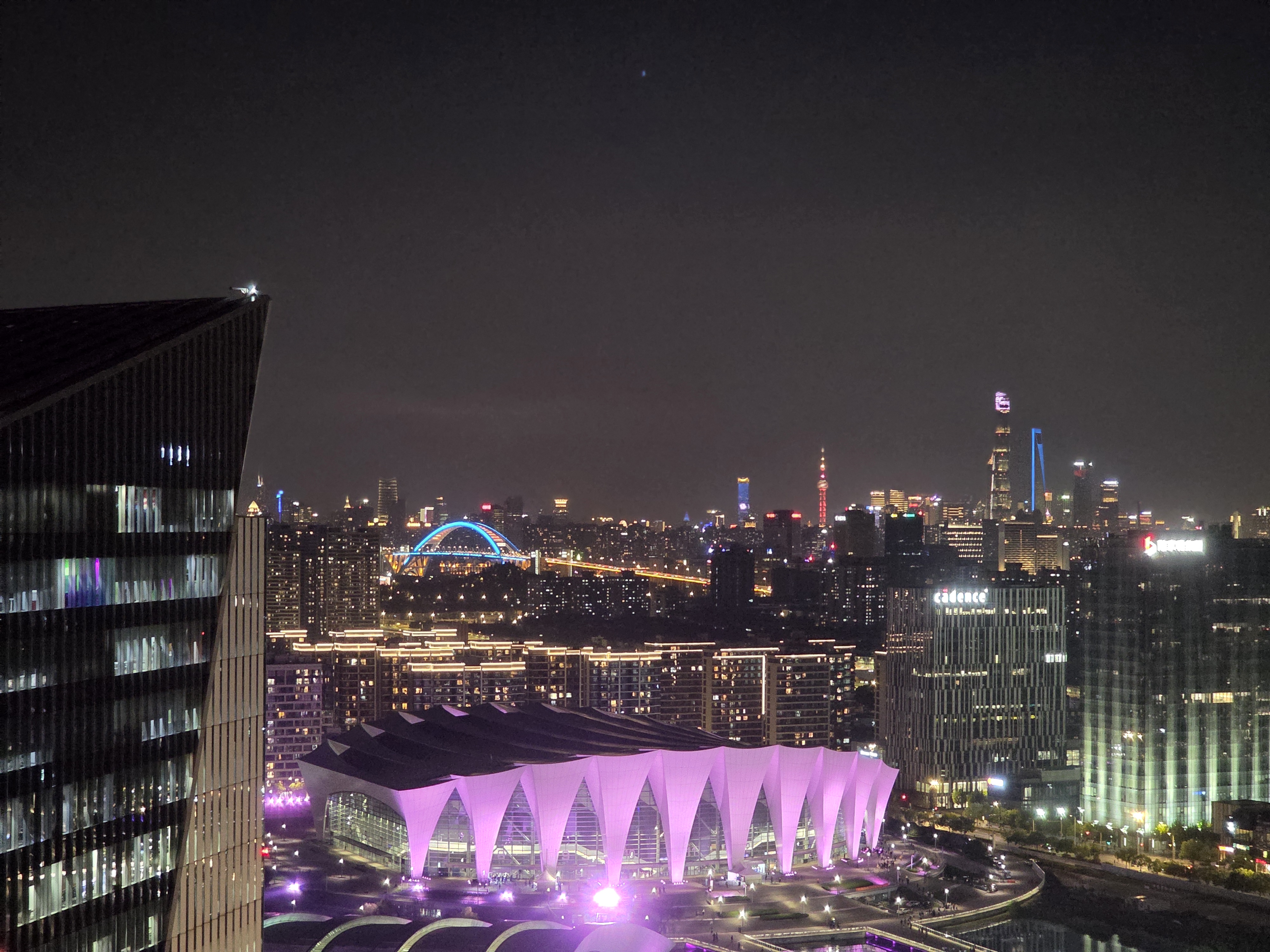 A brightly lit modern building beneath Shanghai's night skyline